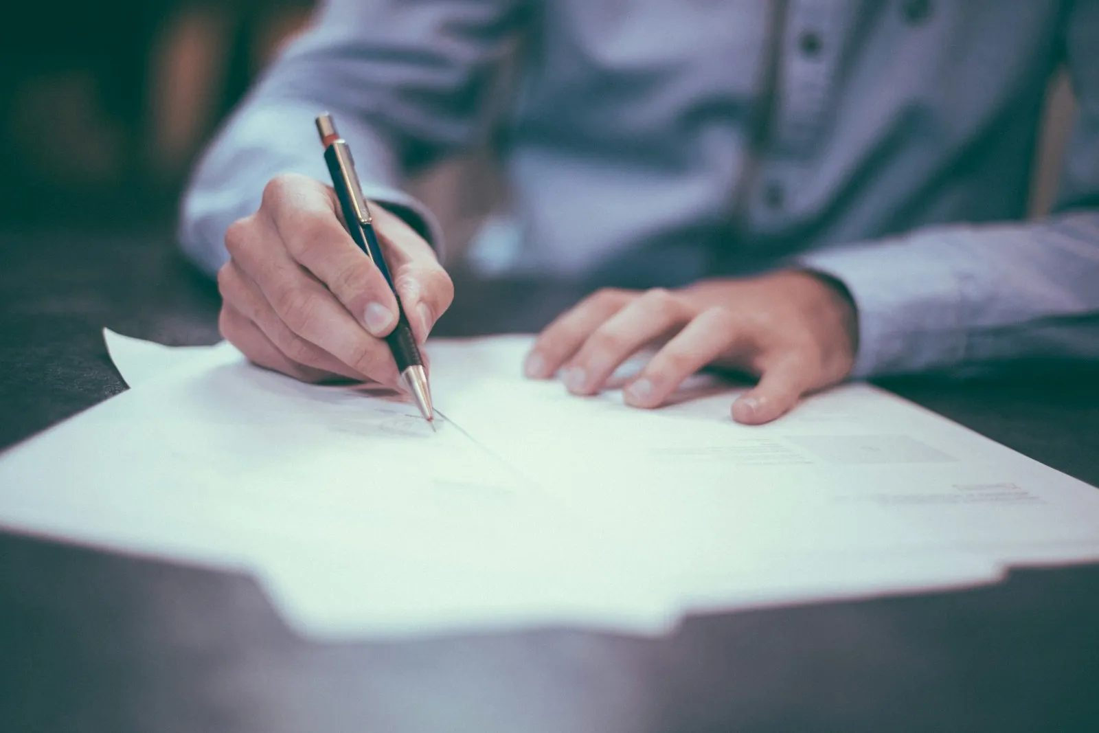 A person writing on a paper document with a pen